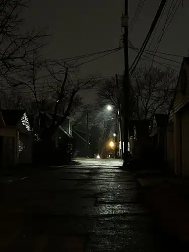 Wet pavement reflects the night's lonely glow.